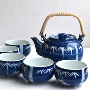 Puede incluir: Un juego de t&eacute; azul y blanco con una tetera y cinco tazas. La tetera tiene un dise&ntilde;o de bamb&uacute; y un asa tejida. Las tazas tambi&eacute;n est&aacute;n decoradas con un dise&ntilde;o de bamb&uacute;.