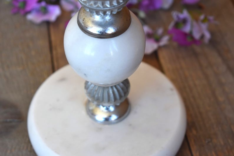 May include: White marble candle holder with a silver base and a decorative top.