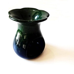 May include: A green and blue ceramic oil burner with a scalloped rim. The burner has a small opening in the centre for a tea light.