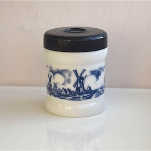 Puede incluir: Tarro de cerámica blanco con tapa negra y diseño azul y blanco de molinos de viento y casas.