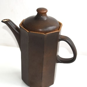 Może przedstawiać: Brązowy ceramiczny dzbanek do kawy z pokrywką i uchwytem. Dzbanek ma ośmiokątny kształt i fakturowaną powierzchnię.