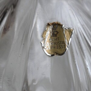 May include: Close-up of a clear glass object with a gold label that reads "Echt Bleikristal Gepresst".