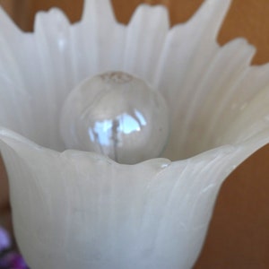 May include: White frosted glass lampshade with a spiky, flower-like design. A light bulb is visible inside the shade.