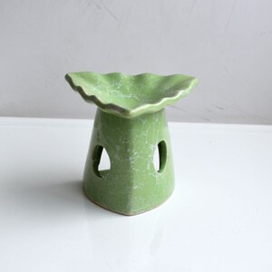 May include: A green ceramic oil burner with a scalloped top and two holes on the side. The burner has a crackled glaze finish.