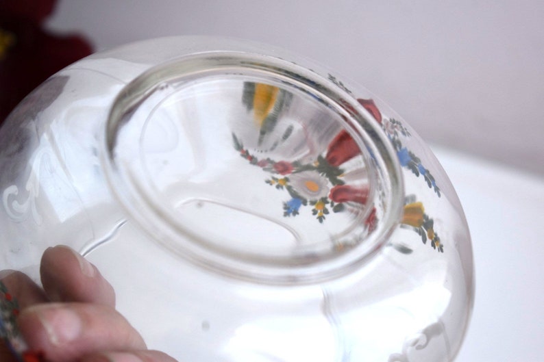 K&ouml;nnte beinhalten: Eine klare Glassch&uuml;ssel mit einem floralen Design, das auf der Au&szlig;enseite bemalt ist. Das Design zeigt rote, gelbe, blaue und gr&uuml;ne Blumen.