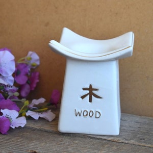 May include: White ceramic incense burner with a gold trim and the word "WOOD" and the Japanese character for "wood" on the front.