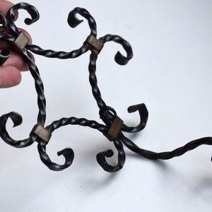 Può includere: Ganci da parete in metallo nero con cinque anelli decorativi e quattro accenti in ottone. Il gancio è attorcigliato e ha un design unico.
