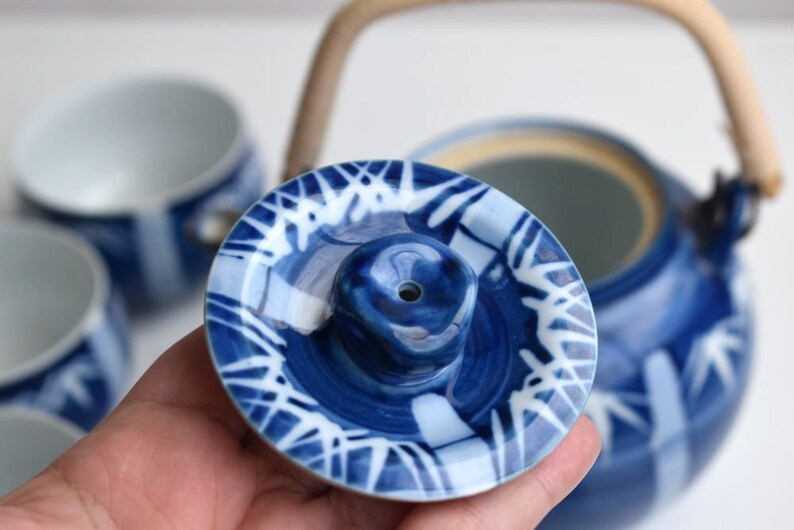 Puede incluir: Tapa de tetera de cer&aacute;mica azul y blanca con un dise&ntilde;o estampado en blanco y azul. La tapa tiene un peque&ntilde;o agujero en el centro.