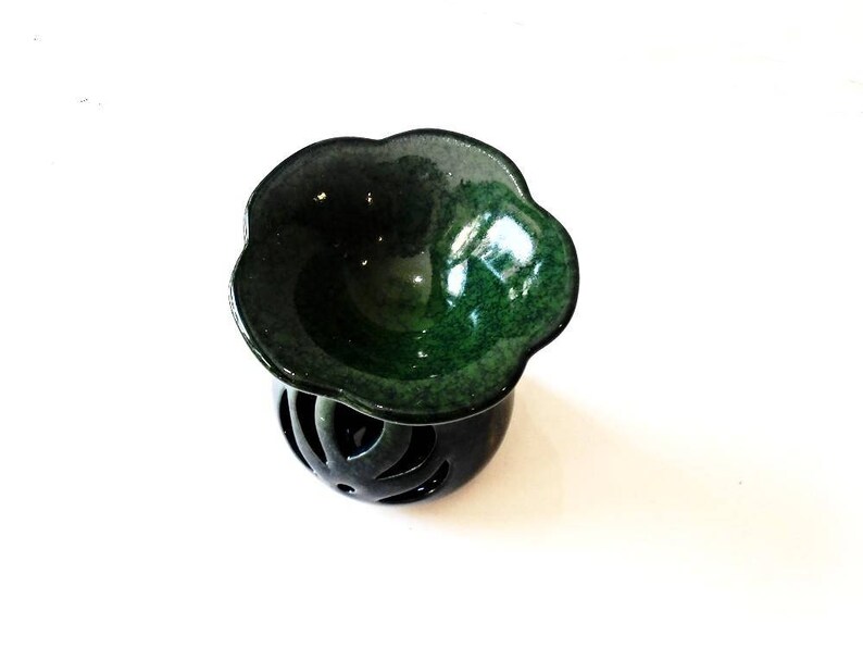 May include: A green ceramic oil burner with a flower-shaped top and a decorative, openwork base.