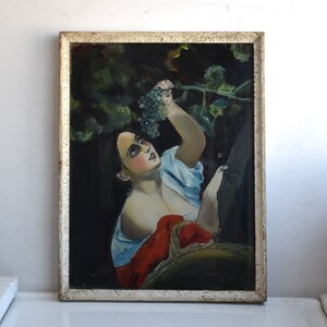 May include: A vintage oil painting on canvas depicting a woman reaching for a bunch of grapes in a vineyard. The woman is wearing a blue and white dress and a red shawl. The painting is framed in a white frame.