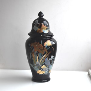 Può includere: Vaso in ceramica nera con coperchio, decorato con motivi floreali dorati e blu. Il vaso ha uno stile asiatico tradizionale.