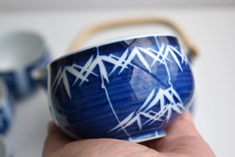 Puede incluir: Una taza de t&eacute; de cer&aacute;mica azul y blanca con un dise&ntilde;o de bamb&uacute;. La taza tiene un asa y est&aacute; hecha de porcelana.