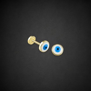 Può includere: Un paio di orecchini d'oro con un design di occhio turco bianco e blu.