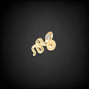 Pode incluir: Brinco de cobra de ouro com um único diamante no olho.