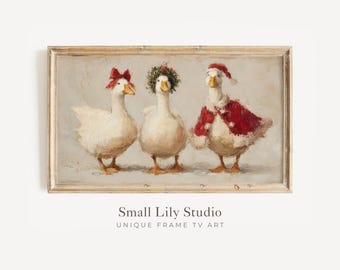May include: A framed painting features three white geese, each adorned with festive accessories. One wears a red bow, another a wreath, and the third a Santa hat and cape. The artwork is labeled "Small Lily Studio UNIQUE FRAME TV ART."