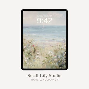 Op de afbeelding: Een zwarte iPad toont een serene strandscène-achtergrond. De digitale kunst toont een lichtblauwe oceaan, een zeilboot en wilde bloemen. De tijd is 9:42 uur op zondag 17 oktober. De tekst "Small Lily Studio IPAD WALLPAPER" staat onderaan.