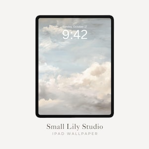 Op de afbeelding: Een zwarte tablet toont een digitale achtergrond met een bewolkte lucht in tinten wit, beige en blauw. De tijd is 9:42 uur en de datum is zondag 17 oktober. De tekst "Small Lily Studio" en "IPAD WALLPAPER" staan onderaan.