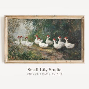 May include: A framed painting depicts a flock of white geese wearing Santa hats in a forest setting. The artwork has a vintage aesthetic with a light brown wooden frame. The text "Small Lily Studio" and "UNIQUE FRAME TV ART" is visible at the bottom.
