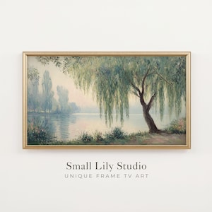 May include: A landscape painting in a gold frame depicting a weeping willow tree by a calm lake at dawn. The scene features soft green and blue tones with hazy trees in the distance. Below the frame, the text reads Small Lily Studio UNIQUE FRAME TV ART.