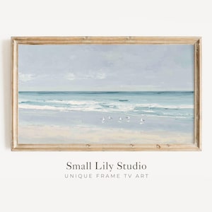 Puede incluir: Pintura enmarcada de una escena de playa con cielo y océano azul claro. La obra representa olas, arena y varias gaviotas. El marco es de madera clara. El texto "Small Lily Studio UNIQUE FRAME TV ART" está en la parte inferior.
