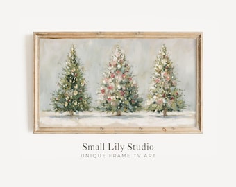 May include: A framed artwork featuring three Christmas trees in a snowy landscape. The trees are decorated with lights and ornaments in shades of green, white, and pink. The artwork is set against a light gray background and framed in a light brown wooden frame.