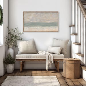 K&ouml;nnte beinhalten: Ein gem&uuml;tliches Interieur mit einer Holzbank, cremefarbenen Kissen und einer Decke. Dar&uuml;ber h&auml;ngt ein gerahmtes Landschaftsbild in ged&auml;mpften T&ouml;nen. Ein gr&uuml;ner Kranz schm&uuml;ckt ein Fenster, und ein dekorativer Korb steht daneben.