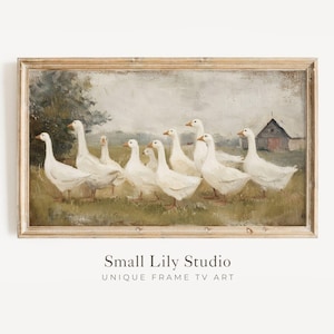 May include: A framed vintage-style painting depicts a flock of white geese walking across a grassy field. A barn is visible in the background. The artwork is set in a light brown wooden frame, evoking a rustic, pastoral theme.
