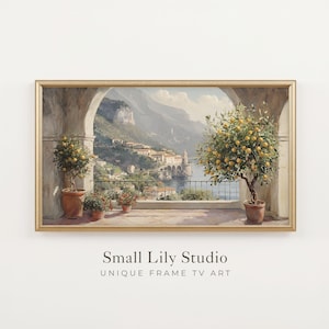 Puede incluir: Una pintura de paisaje en un marco dorado que representa una terraza costera con dos limoneros en macetas, arcos de piedra y una vista de un pueblo mediterráneo en un acantilado. El texto Small Lily Studio UNIQUE FRAME TV ART está debajo.