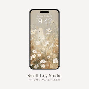 Op de afbeelding: Een smartphone met een digitale achtergrond waarop een spookfiguur in een veld met witte en beige bloemen staat. Het scherm toont de tijd 9:42 en de datum Sunday, October 17. Onder de telefoon staat de tekst Small Lily Studio PHONE WALLPAPER.