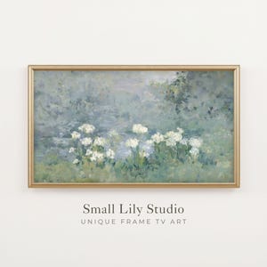 May include: A rectangular landscape painting in a thin gold frame featuring an impressionistic scene of white flowers against a soft blue and green background. Below the frame, the text reads Small Lily Studio UNIQUE FRAME TV ART.