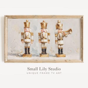 May include: A framed print featuring three toy nutcracker soldiers in white and gold uniforms. The painting has a textured, impressionistic style with a light background. One soldier holds a trumpet. The frame is gold. The text "Small Lily Studio" is at the bottom.