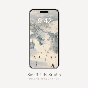 Op de afbeelding: Een smartphone toont een winterlandschap wallpaper met skiërs op een besneeuwde berg. De tijd is 9:42 uur op zondag 17 oktober. De telefoon is zwart omlijst, met de tekst "Small Lily Studio PHONE WALLPAPER" onderaan.