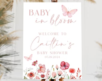 Puede incluir: Un cartel blanco con texto rosa e ilustraciones florales. El texto dice "Baby in Bloom" y "Bienvenido a la Baby Shower de Caitlin 02.18.2024".