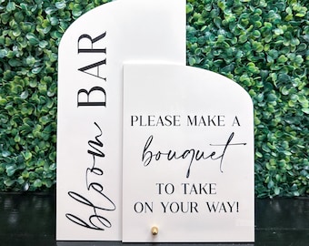 May include: White sign with black text that reads "bloom bar" and a smaller white sign with black text that reads "Please make a bouquet to take on your way!"