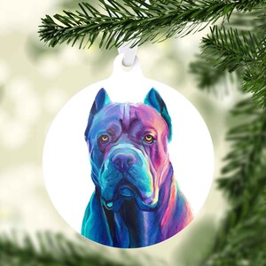 May include: A colorful, iridescent Christmas ornament featuring a Cane Corso dog breed. The dog's fur is painted in shades of blue, purple, and pink, with a white background.