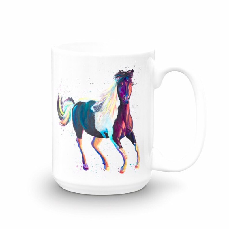 Puede incluir: Taza de cer&aacute;mica blanca con una pintura colorida de un caballo corriendo. El caballo es marr&oacute;n y blanco con una larga melena y cola blancas. El fondo es blanco con algunos puntos coloridos.