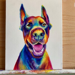 May include: A colorful painting of a dog with rainbow fur. The dog is looking up and has its mouth open, showing its teeth. The background is white.