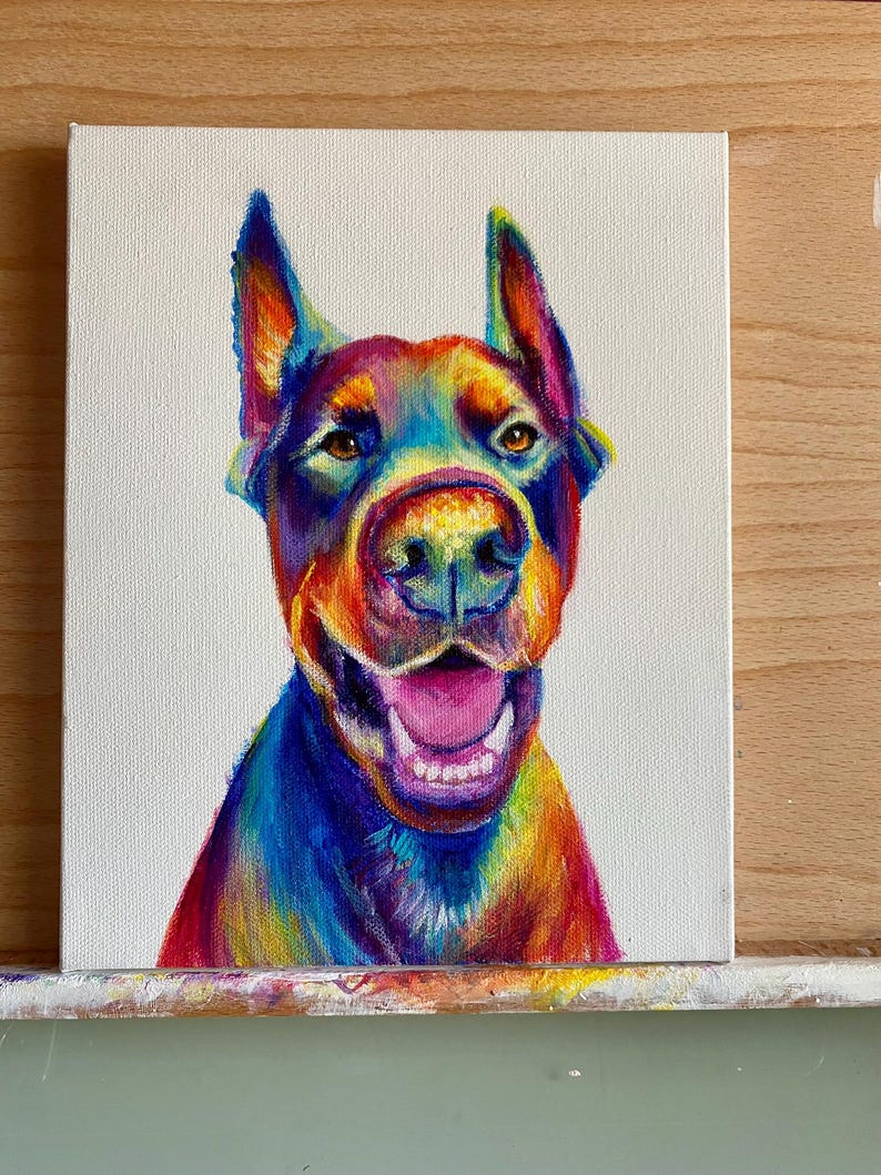 May include: A colorful painting of a dog with rainbow fur. The dog is looking up and has its mouth open, showing its teeth. The background is white.