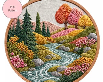 Op de afbeelding: Een gedetailleerde borduursel van een landschap met een kronkelende rivier, kleurrijke heuvels en bomen in groen, oranje, roze en geel. Het kunstwerk is geplaatst in een houten borduurring. Een roze cirkel met de tekst "PDF Pattern" staat linksboven.