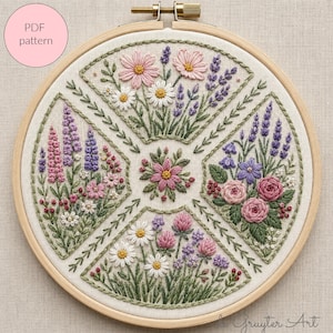 May include: A circular wooden embroidery hoop containing a fabric panel with a hand-stitched floral design. The embroidery features four distinct sections of colourful wildflowers, including pink, purple, and white blossoms, surrounding a central flower.