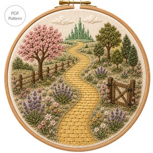 May include: An embroidery hoop containing a fabric panel with a stitched landscape featuring a yellow brick path leading to a green castle, a pink flowering tree, lavender bushes, daisies, a wooden fence, and a gate, with text reading PDF Pattern.