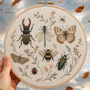 May include: A circular wooden embroidery hoop containing a fabric panel with detailed thread-stitched insects including a stag beetle, dragonfly, butterfly, bumblebee, ladybug, and moth, surrounded by embroidered botanical sprigs and text reading PDF pattern.