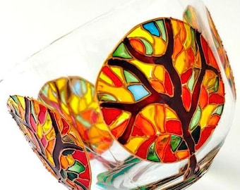 May include: A clear glass bowl decorated with hand-painted tree motifs featuring a stained-glass effect. The trees have dark brown outlines and are filled with vibrant, translucent segments of yellow, orange, red, green, and blue paint.