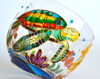 May include: A clear glass bowl featuring a hand-painted sea turtle with a vibrant shell in shades of green, yellow, orange, and blue. The design includes gold outlines, purple coral, and blue water accents, creating a colorful underwater scene.