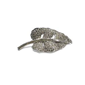Broche vintage de plata rodiada de los años 40, con hoja incrustada en pasta de cristal transparente, elegante y llamativo, en tarjeta original.