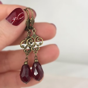 Pendientes de bronce con cristales rojos oscuros y diseño floral en forma de lágrima