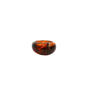 May include: A brown and black resin ring with a swirl pattern.