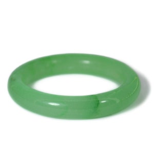 May include: A smooth, green jade bangle bracelet. The bangle is made from a single piece of jade and has a polished finish.