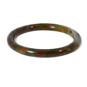 May include: A smooth, circular bangle bracelet featuring a polished finish with a mottled pattern of deep forest green, earthy brown, and muted orange tones throughout the entire surface of the solid, rounded band structure.