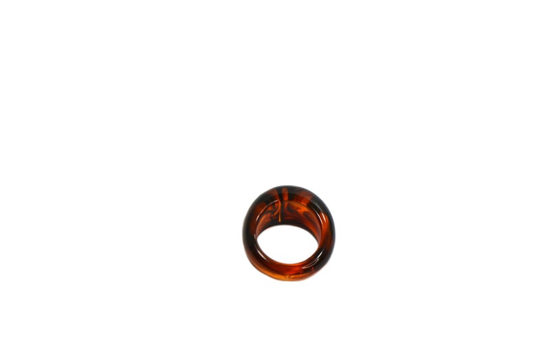 May include: A brown tortoiseshell ring with a smooth, rounded surface.
